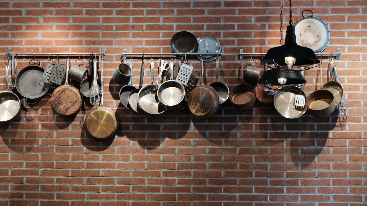 pots and pans hanging on a red brick wall